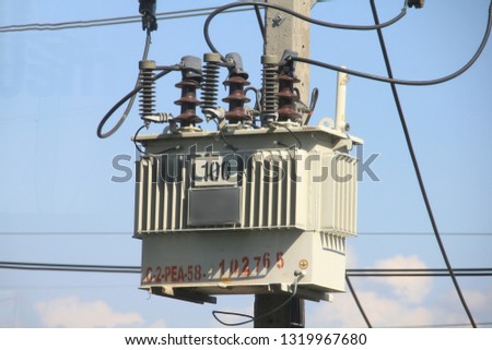 Electric tranformer installed on the eletric ploe tower while electric cables crossing blue clouds in the sky in thailand Royalty-Free Stock Photo #1319967680