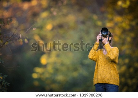 Female photographer taking pictures outdoor on a lovely autumn day - shallow DOF, color toned image