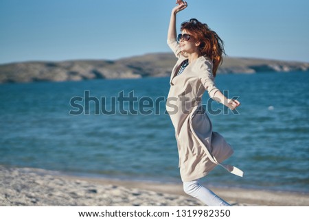 Happy woman on nature jumps up near the sea on the sandy shore