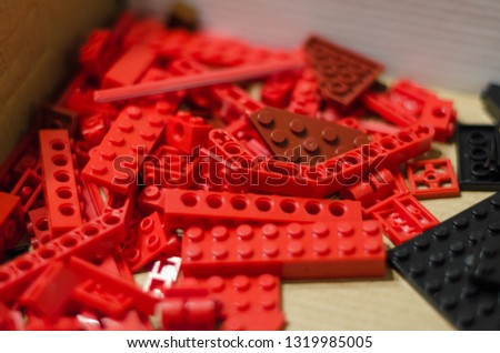 Red toy bricks for kids on the floor background. Playing in plastic lego concept. Pieces and elements of constructor toys.