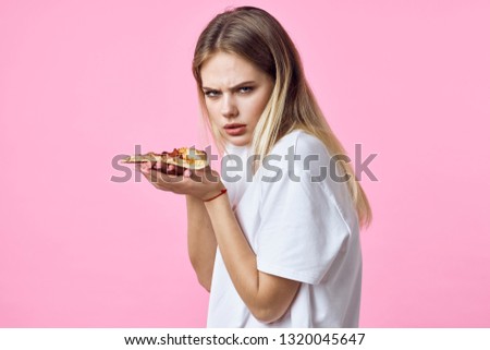 A woman with a bird in her hand and a white T-shirt offendedly looks into the camera on a pink background
