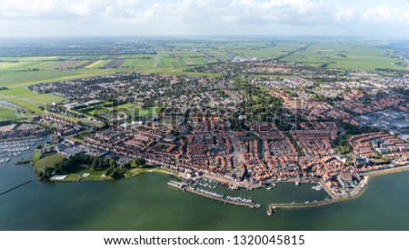 Aerial view of the city of Edam Volendam at lake Markermeer in The Netherlands. A typical dutch fisher village with a marina and an old fishermans wharf. On the horizon a blue sky with cloud streets.