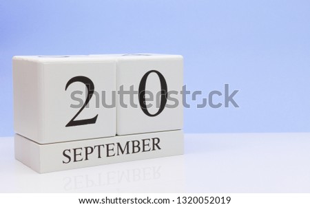 September 20st. Day 20 of month, daily calendar on white table with reflection, with light blue background. Autumn time, empty space for text