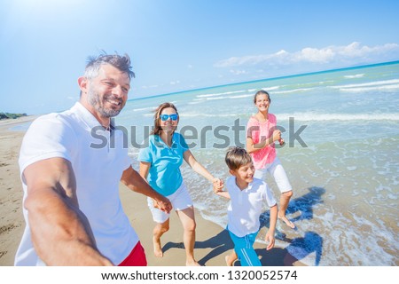 Happy family of four having fun at beach together. Fun happy lifestyle in the summer leisure