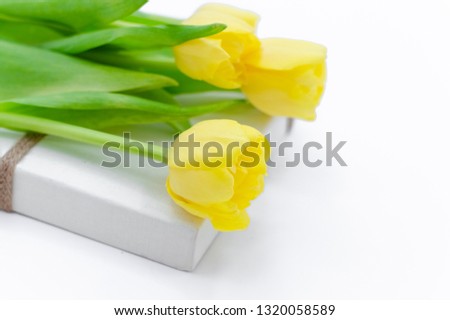 Bouquet of yellow Spring tulips lying on white gift box isolated on white background.Top horizontal view copyspace