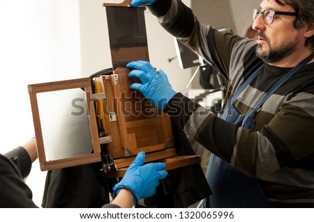 Photographer sets an old large format camera with photographic plate chassis, before the shooting.