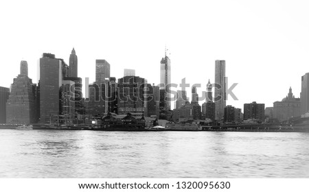 New York Financial District and the Lower Manhattan at dawn viewed from the Brooklyn Bridge Park. High key black and white image.