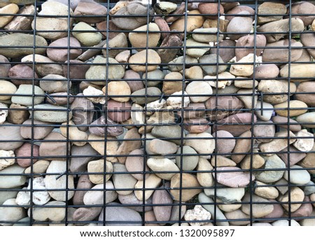 Stones in wire mesh. Popular element of design for garden landscaping.Background of Stone and steel.