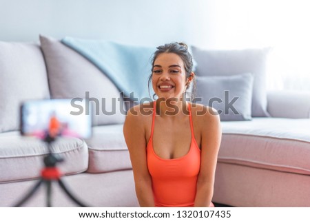 Sport blogger recording video for vlog. Gorgeous female coach and blogger giving fitness advice to her followers on video. Beautiful sporty woman vlogger making new video at home 