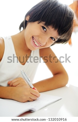 Boy writing on paper at his school and doing schoolwork