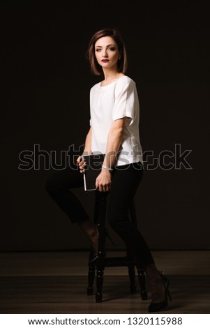 Pretty young woman posing with a diary or book in studio on the black background