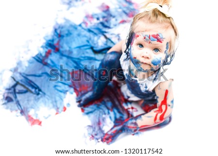 An adorable little toddler, girl has fun playing with colouring paints, getting covered in paint having lots of fun, shot on a white background, and in a home setting, family portrait arts & crafts