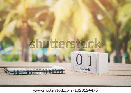 close up wooden calendar, notebook and pencil on old wood table, 01 march text, first day of month, vintage tone