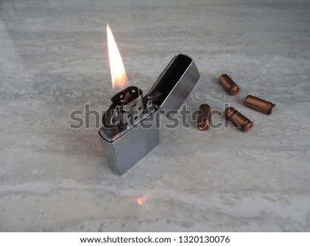 Open metal lighter with flame on black background.