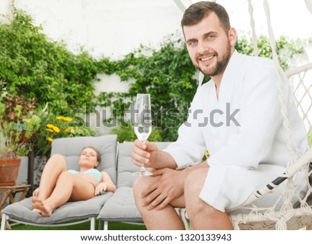 Young happy man spending romantic day with girlfriend outdoors at spa resort. Focus on man 