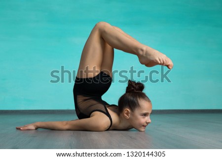 Acrobat standing in back bend pose on green background.  Yoga backbend gymnastics, girl gymnast  in back bend bherundasana pose.