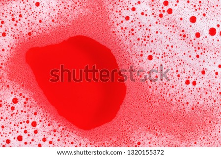 Foam with bubbles on red background. Shampoo or detergent in water. Flat lay.