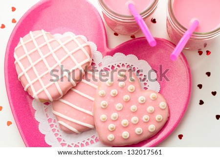 Pink Valentine cookies on a pink plate with glasses of strawberry milk