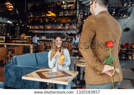 couple, relationships and people concept - happy woman looking at man hiding bunch of roses behind his back
