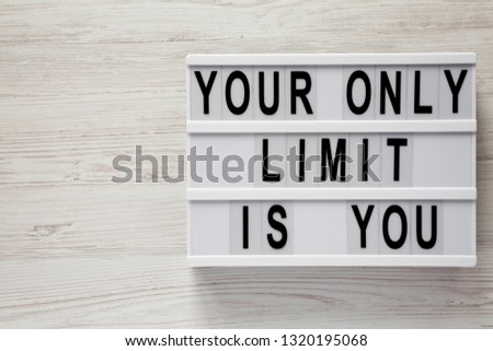 Lightbox with text 'Your only limit is you' on a white wooden background, top view. From above, flat lay, overhead. Copy space.