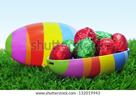 an easter egg of different colors, full of chocolates, on the grass
