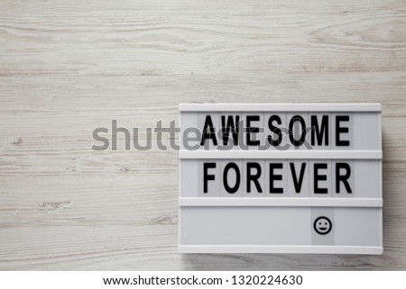 'Awesome forever' word on lightbox on a white wooden background, top view. From above, flat lay, overhead. 