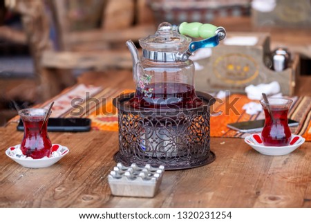 Turkish tea in traditional glasses on table. Traditional Turkish tea set: glass cup of tea, painted teapot.