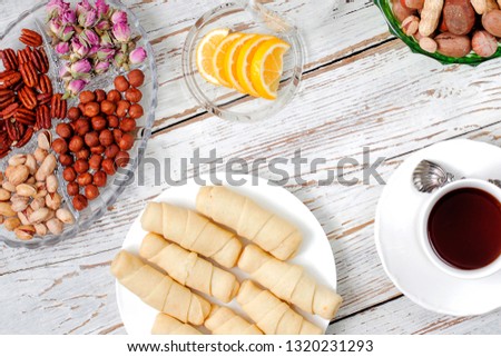Traditional Azerbaijan holiday Novruz cookies mutaki on white plate on the white background with nuts and a cup of tea,lemon,flat lay,top view,space for copy