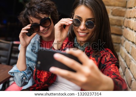 Two girls taking selfies from above. Girls taking selfies at a coffee shop. Two friends posing for a selfie.
