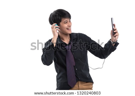 Young teenage listen music with ear phone,hand holding mobile phone and looking at camera take photo isolate on white background,feel happy 