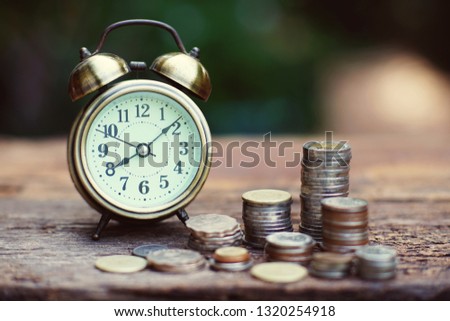 Vintage golden alarm clock with stacks of coin. Time and money for financial concept. Copy space. Royalty-Free Stock Photo #1320254918