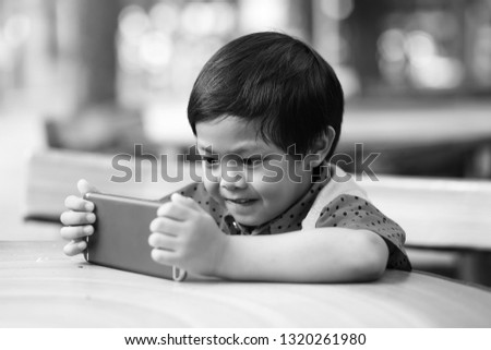 An Asian boy watching cartoon on a smart phone, black and white tone.
