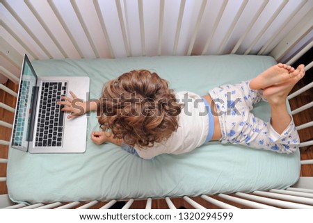 Young child 4 years old in the bed looks lap top computer during n-cov 19 Coronavirus