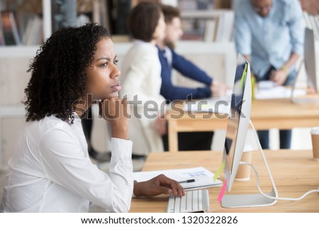 Diverse people in office area, focus on pensive african employee woman sitting at desk in front of pc, thinking analyzing market. Puzzled biracial worker having doubts trying to solve business problem Royalty-Free Stock Photo #1320322826