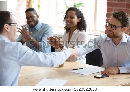 Business partners sitting at desk in boardroom, representatives shaking hands express respect and gratitude with hand gesture. Company executives reach agreement feels satisfied after signing contract Royalty-Free Stock Photo #1320322853