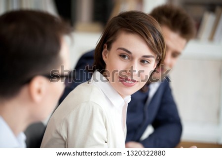 Young caucasian specialists staff sitting together in office conference room talking, discussing working moments, close up focus on smiling attractive woman team leader listening opinion of colleague Royalty-Free Stock Photo #1320322880