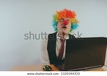 Office worker in clown wig, clown concept at work. Businessman at the computer, work on a laptop
