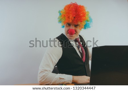 Office worker in clown wig, clown concept at work. Businessman at the computer, work on a laptop
