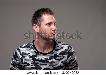 Confident handsome adult young muscular man looking away at copy space on gray background. 