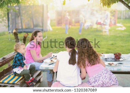 Picture of four kids sitting by the table in nature and eating.