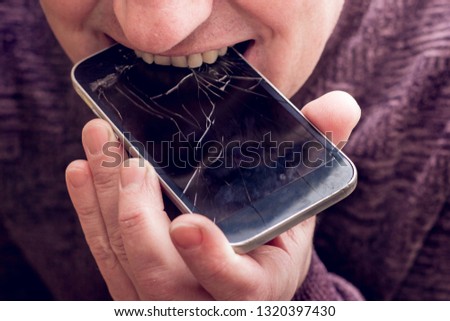 A man bites a broken phone. Phone with broken glass
