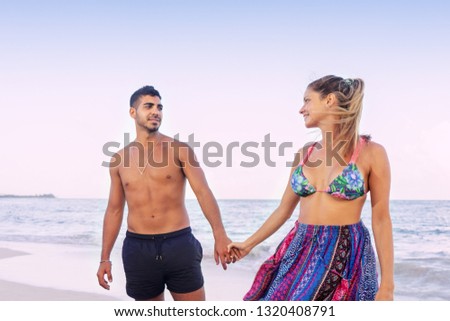 Lifestyle portrait of young couple holding their hands at the beach