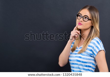 Thoughtful young woman thinking about something on a black background