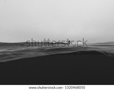 A surfer on a backside wave trimming along the water. The foreground shows the cold dark waters below and the sky is grey and moody. Taken at Bournemouth Beach 