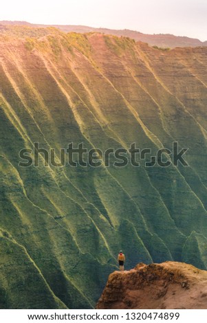 Man Standing on the edge of a cliff and enjoys the sunset on Hawaii, Kauai, Na pali coast.