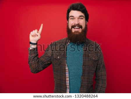 Young man wearing casual clothes over isolated background with a big smile on face, pointing with hand and finger up and looking at the camera.