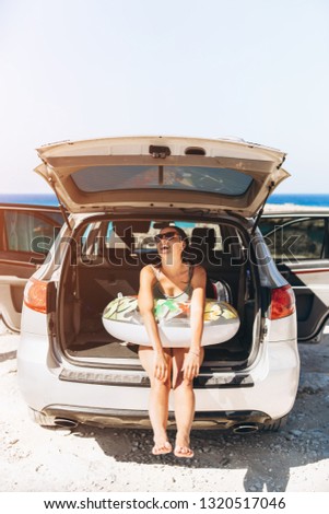 Pretty pan asian brunette with float near car trunk at the seaside beach