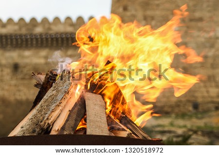 Traditional Novruz holiday bonfire with old brick palace wall as background, close-up. 