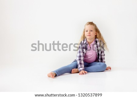 A white-haired girl sits on the floor in jeans and a plaid shirt. Emotions on the photo.
