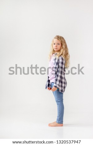 A girl with white hair jumps in jeans and a plaid shirt. Emotions on the photo